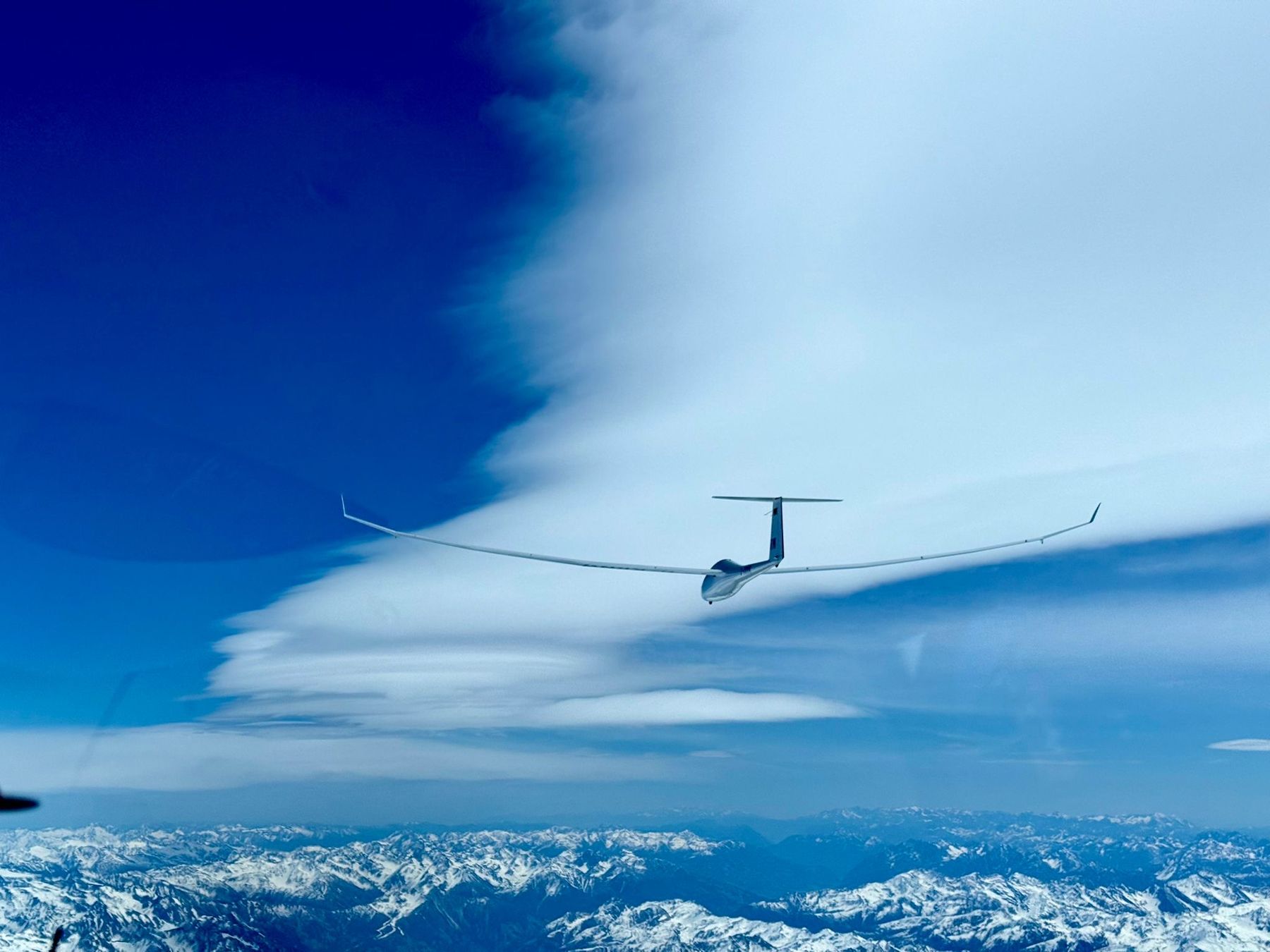Segelflugzeug auf Streckenflug über den verschneiten Alpen
