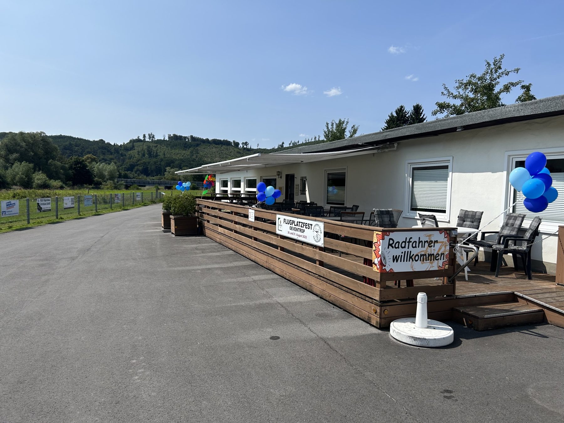 Vereinsheim Spatzennest mit Sonnenterrasse, Markise und dem Schild „Radfahrer willkommen“