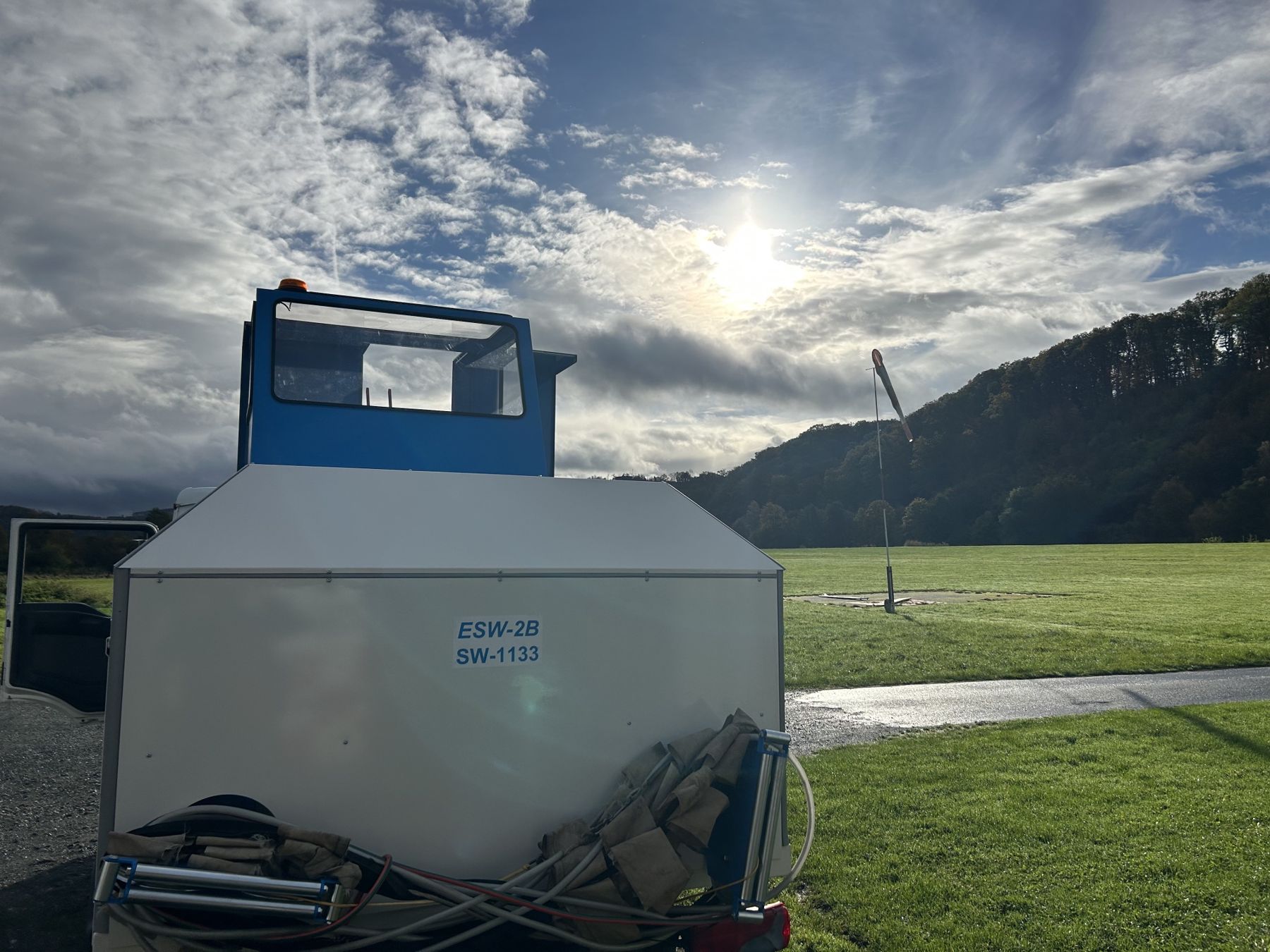 Elektrowinde ESW-2B von hinten, daneben der Windsack am Flugfeld